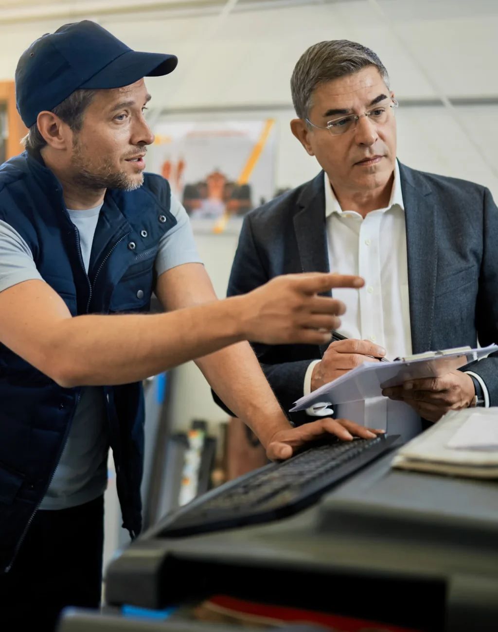 gerente-adulto-medio-y-mecanico-de-automoviles-hablando-mientras-usa-una-computadora-en-un-taller-de-reparacion-de-automoviles